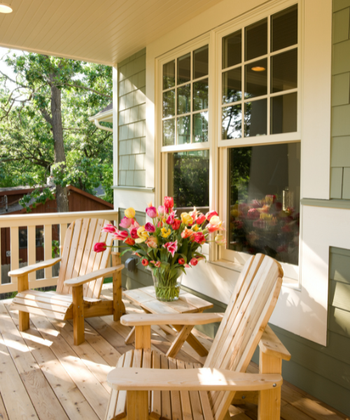 A vase of flowers sitting on a table on a porch