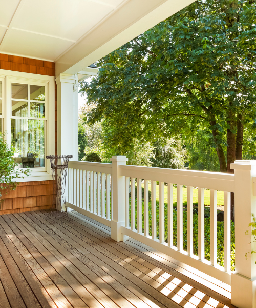 A porch with a white railing and a potted plant