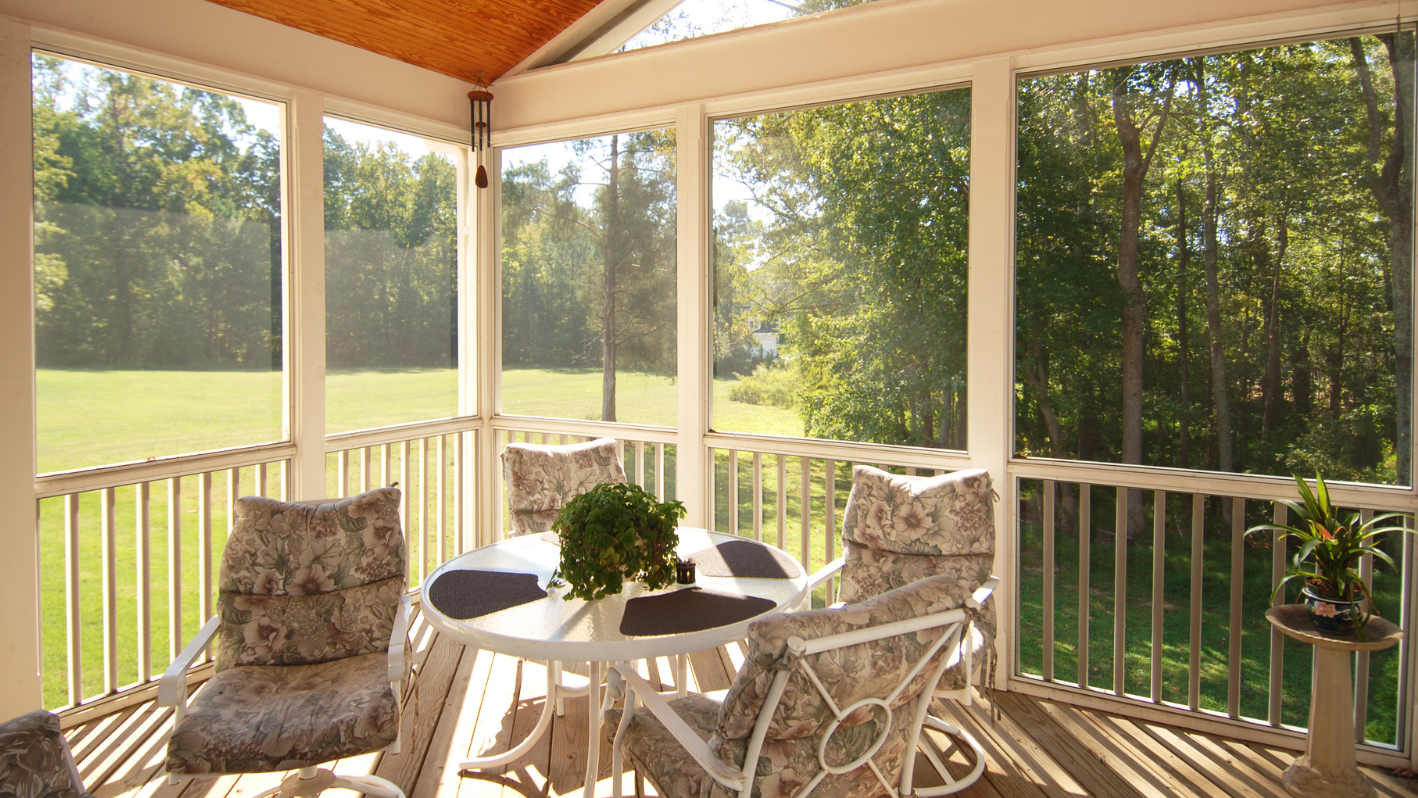 A screened porch with chairs and a table